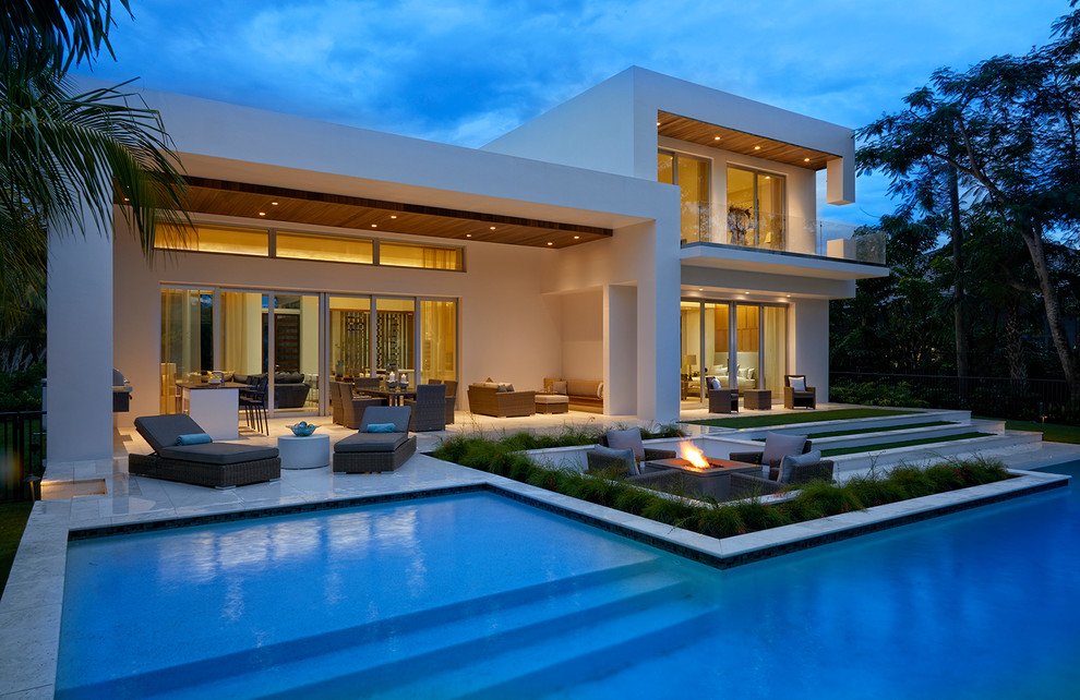 Hot tub - mid-sized modern backyard stone and l-shaped infinity hot tub idea in Miami