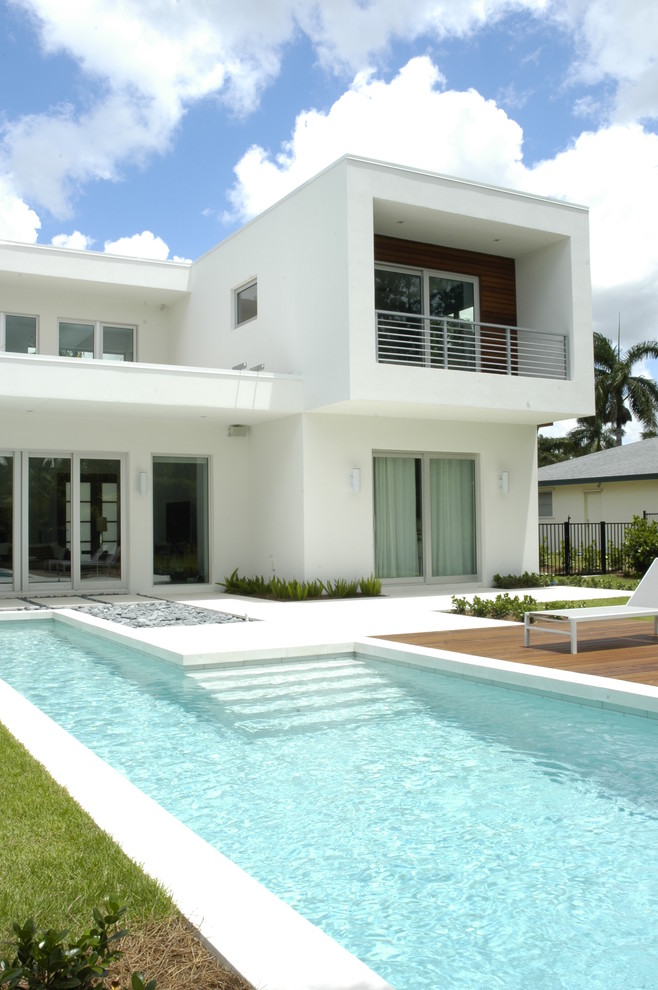 Photo of a large modern back l-shaped lengths swimming pool in Miami with a water feature and concrete paving.