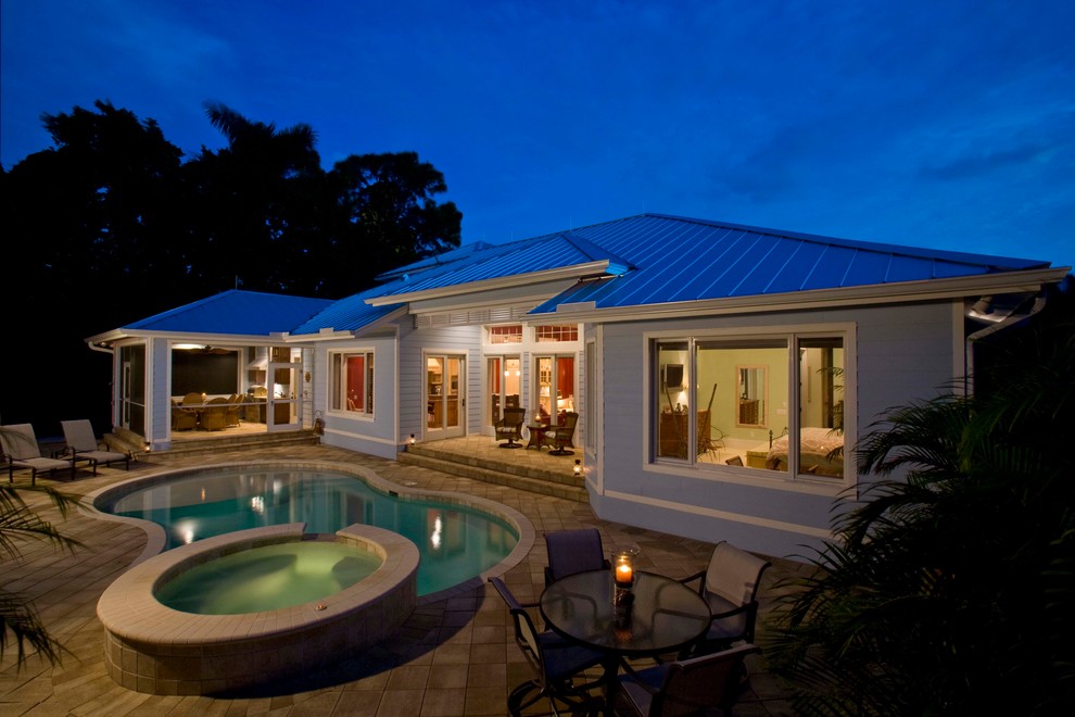 Example of an island style backyard hot tub design in Miami