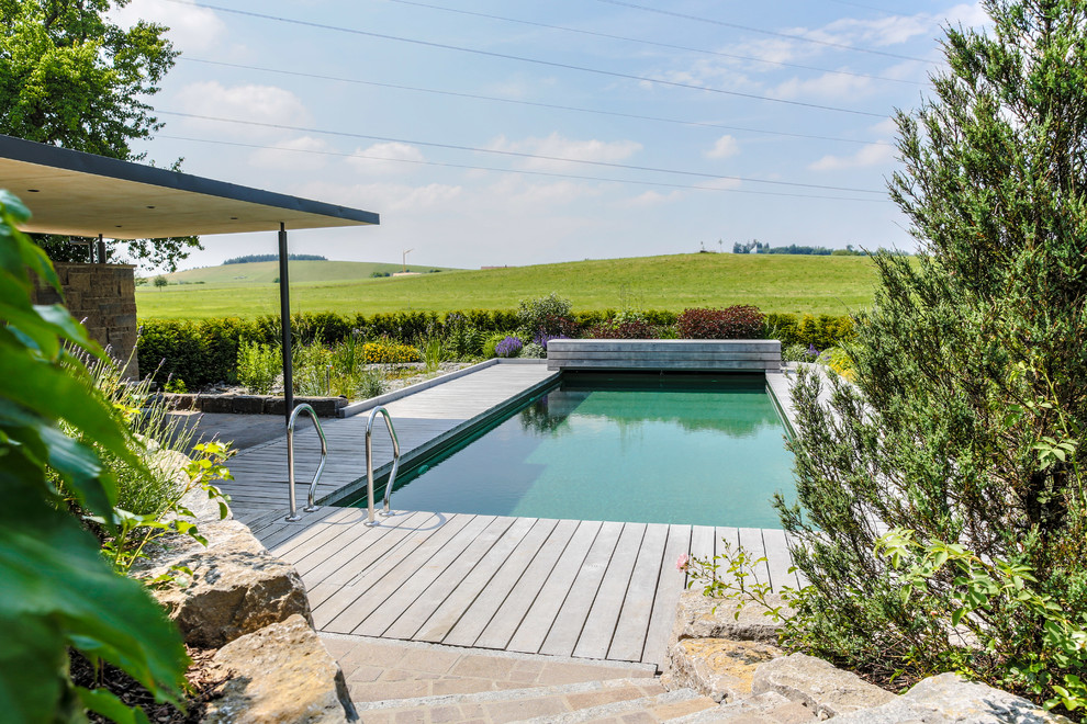 Foto de piscina alargada de estilo de casa de campo de tamaño medio rectangular en patio trasero con entablado