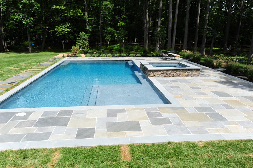 Ejemplo de piscinas y jacuzzis alargados tradicionales grandes rectangulares en patio trasero con adoquines de piedra natural