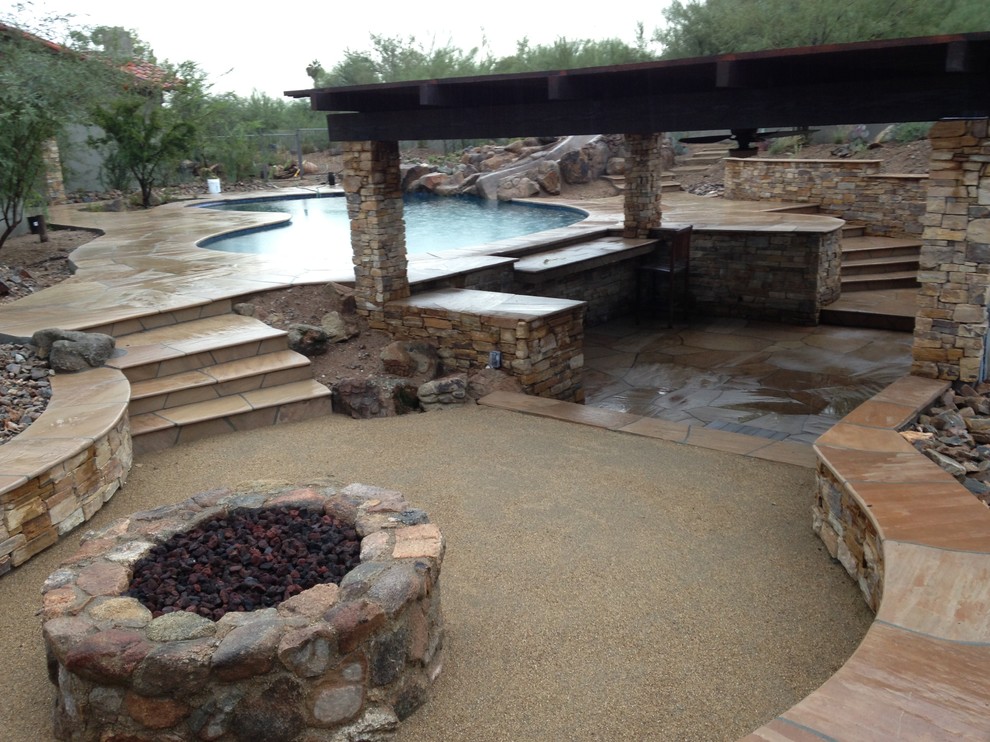 Foto de piscina con tobogán alargada de estilo americano de tamaño medio a medida en patio trasero con adoquines de piedra natural