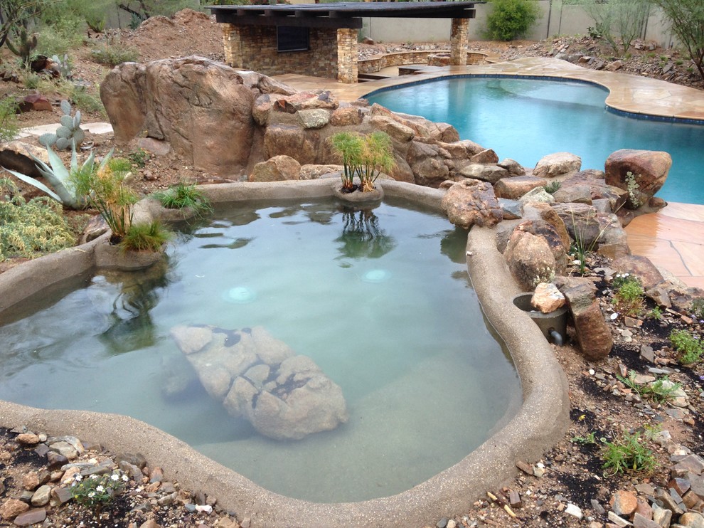 Esempio di una piscina monocorsia stile americano personalizzata di medie dimensioni e dietro casa con una vasca idromassaggio e pavimentazioni in pietra naturale