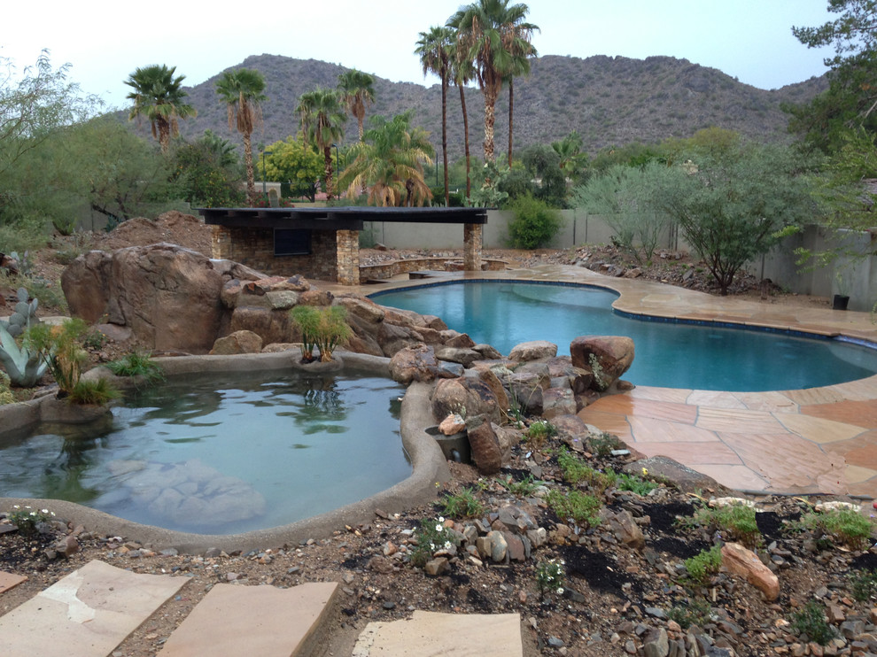 Ejemplo de piscinas y jacuzzis alargados de estilo americano de tamaño medio a medida en patio trasero con adoquines de piedra natural