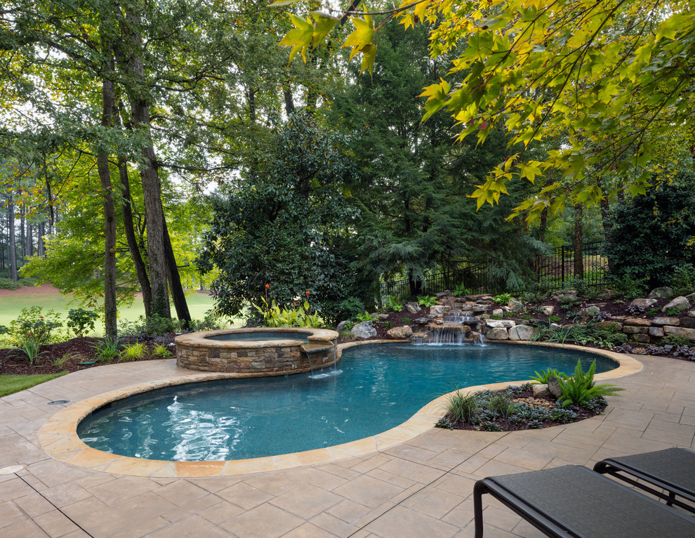 Foto di una piscina naturale chic personalizzata di medie dimensioni e dietro casa con una vasca idromassaggio e pavimentazioni in pietra naturale