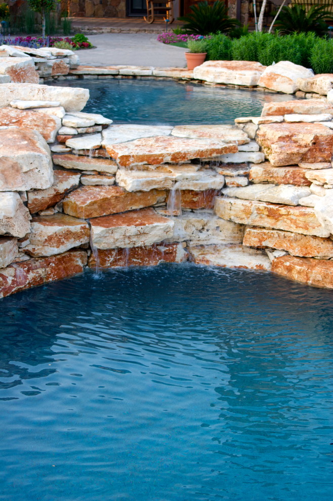 Ispirazione per un'ampia piscina naturale rustica personalizzata dietro casa con fontane e pavimentazioni in pietra naturale