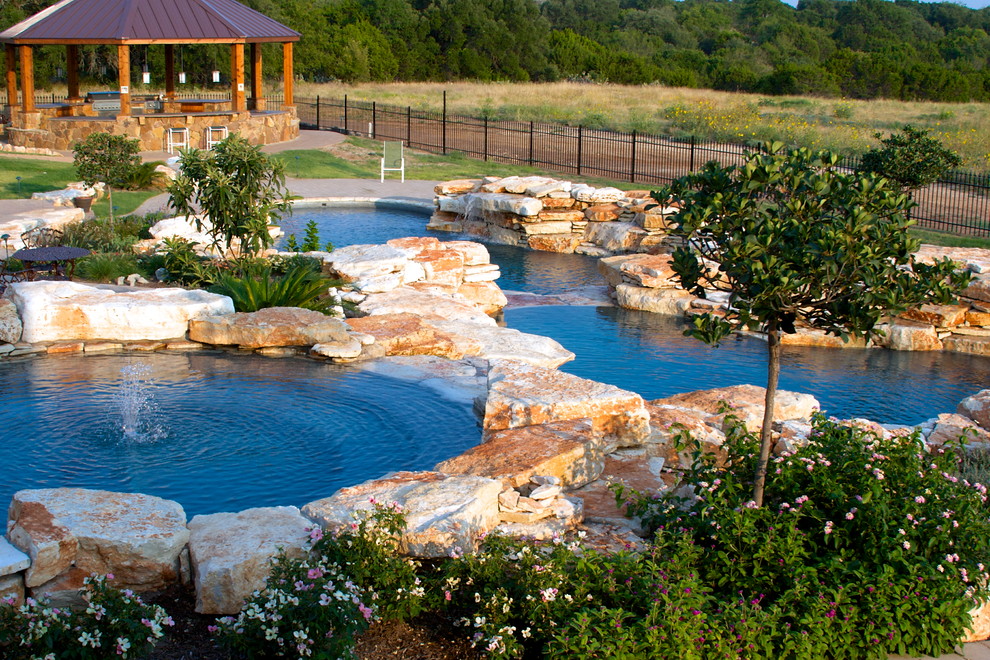 Huge mountain style backyard stone and custom-shaped natural pool fountain photo in Dallas