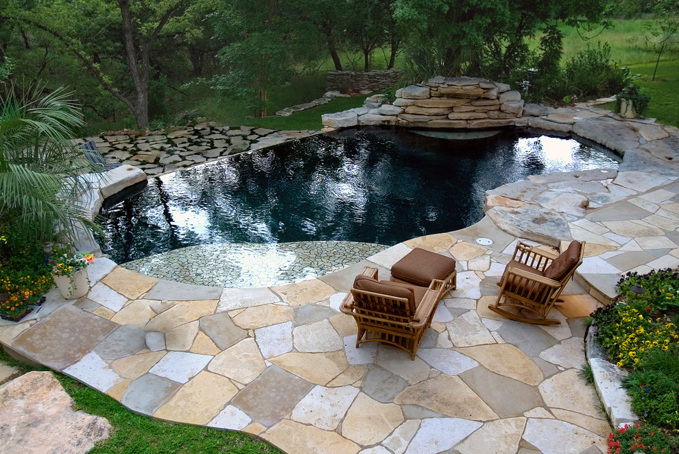 Imagen de piscina con fuente infinita tropical grande a medida en patio trasero con adoquines de piedra natural