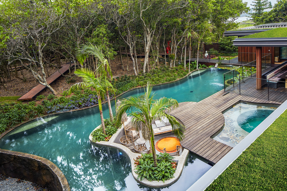 Ejemplo de piscina infinita exótica a medida en patio trasero con entablado