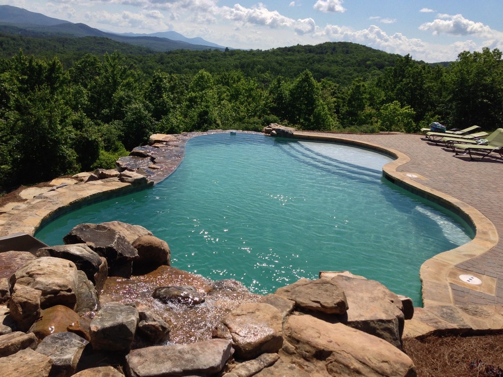 Imagen de piscina con fuente natural de estilo americano extra grande a medida en patio trasero con adoquines de ladrillo