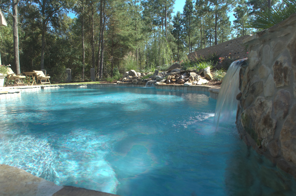 Imagen de piscinas y jacuzzis naturales de estilo americano grandes a medida en patio trasero con adoquines de piedra natural