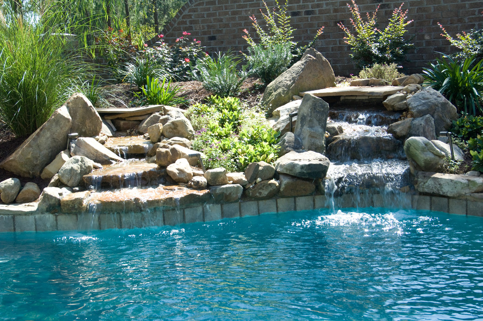 Inspiration pour une grande piscine naturelle et arrière craftsman sur mesure avec un bain bouillonnant et des pavés en pierre naturelle.