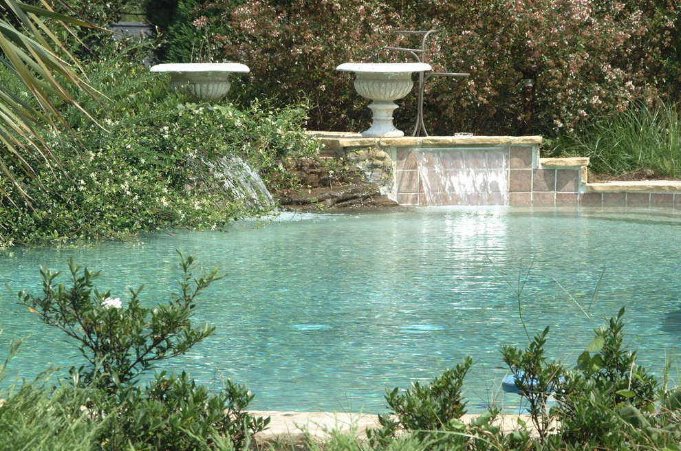 Diseño de piscinas y jacuzzis naturales de estilo americano grandes a medida en patio trasero con adoquines de piedra natural