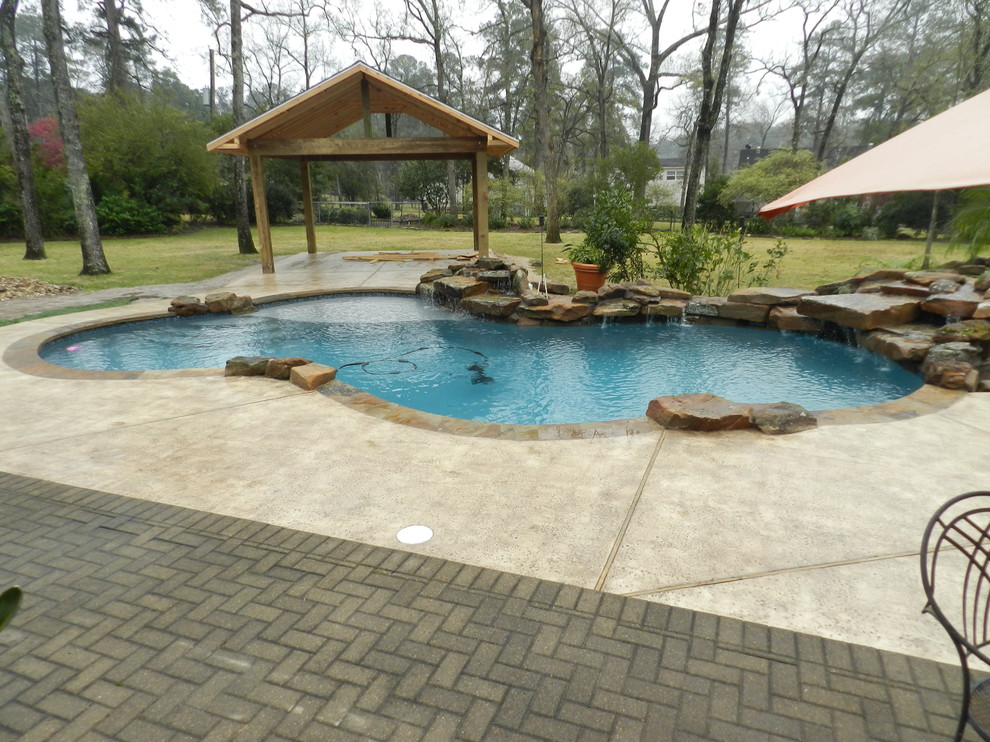 Example of a mid-sized mountain style backyard stamped concrete and custom-shaped natural pool fountain design in Houston