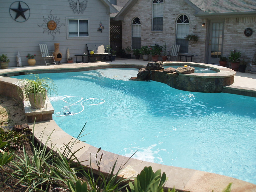 Pool - rustic backyard stamped concrete and custom-shaped pool idea in Houston
