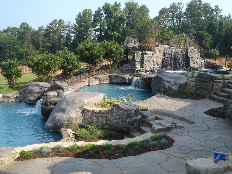 Réalisation d'une grande piscine naturelle et arrière chalet sur mesure avec un point d'eau et des pavés en pierre naturelle.