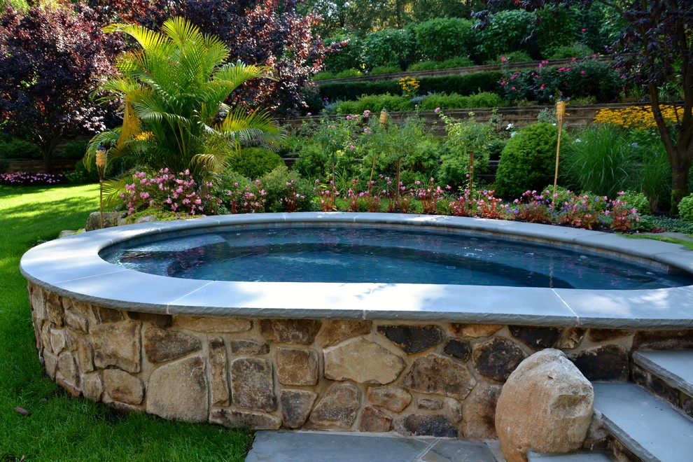 На фото: естественный бассейн среднего размера, в форме фасоли на заднем дворе в стиле рустика с джакузи и покрытием из каменной брусчатки