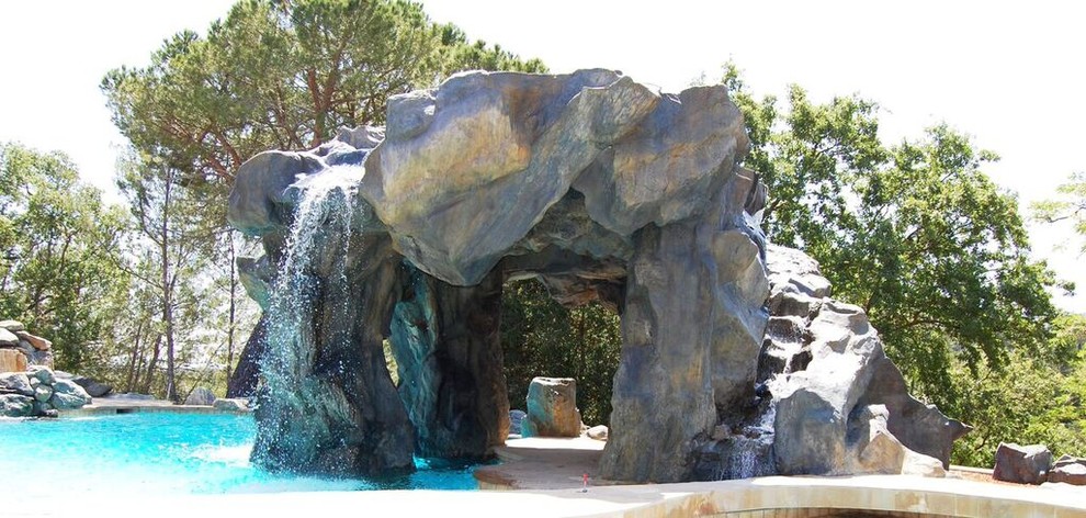 Ejemplo de piscina con fuente natural tradicional grande a medida en patio trasero con adoquines de piedra natural