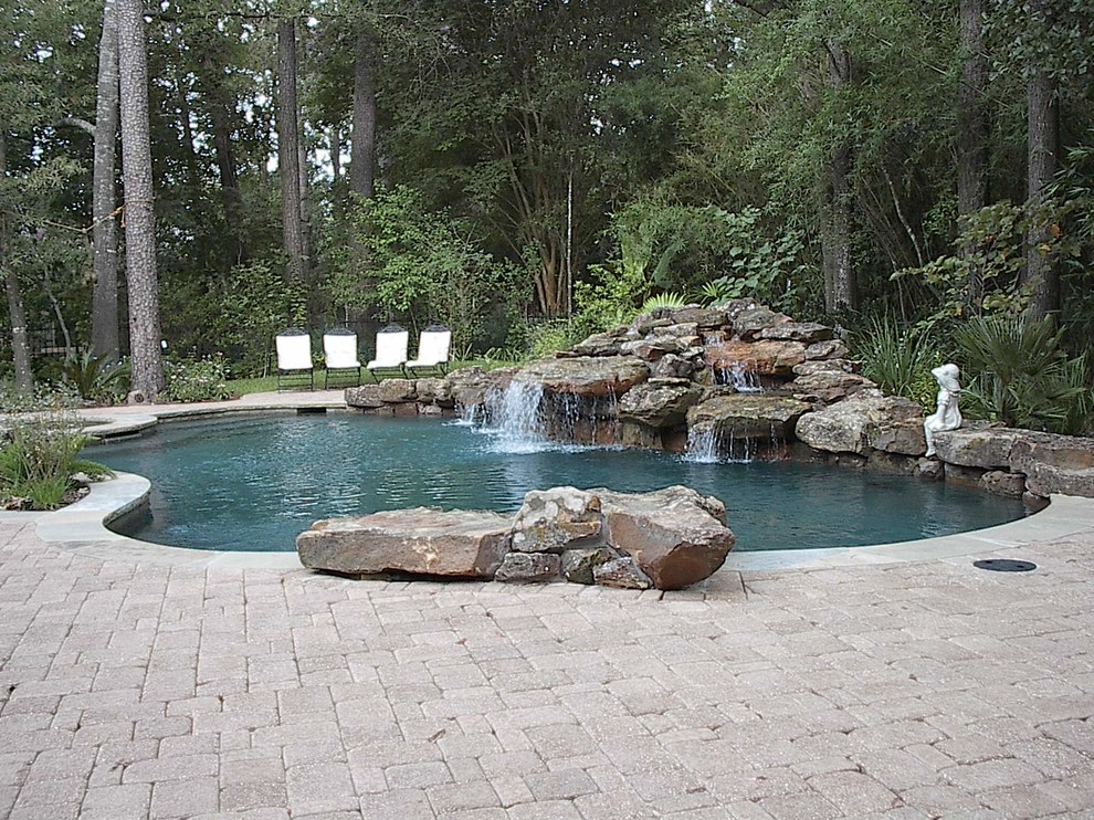 Foto di una grande piscina tropicale personalizzata dietro casa con fontane e pavimentazioni in cemento