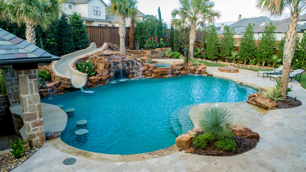 Idee per una piscina tropicale personalizzata di medie dimensioni e dietro casa con un acquascivolo e pavimentazioni in pietra naturale