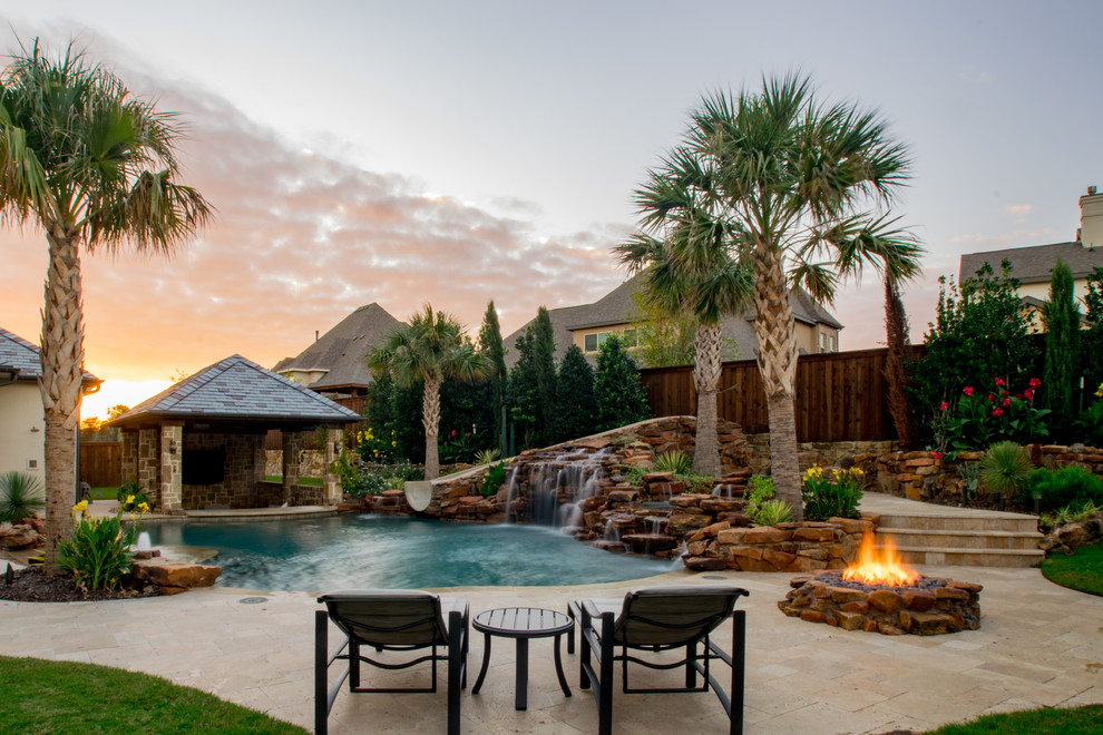 Ejemplo de piscina con tobogán exótica de tamaño medio a medida en patio trasero con adoquines de piedra natural