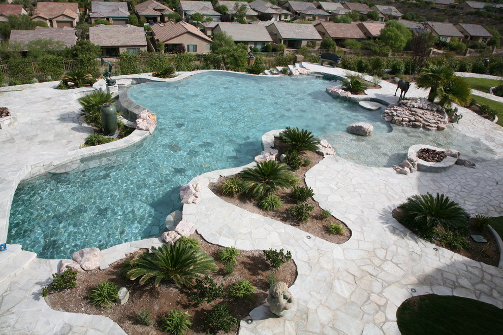 Immagine di una grande piscina a sfioro infinito stile marino personalizzata dietro casa con fontane e pavimentazioni in pietra naturale