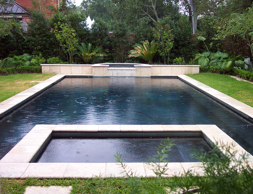 Immagine di una grande piscina monocorsia minimalista rettangolare dietro casa con fontane e pavimentazioni in pietra naturale