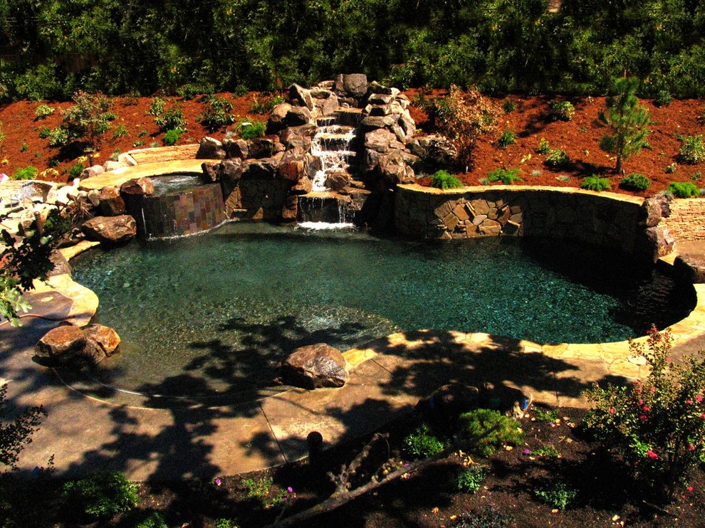 Esempio di una grande piscina naturale stile marinaro personalizzata dietro casa con una vasca idromassaggio e pavimentazioni in pietra naturale