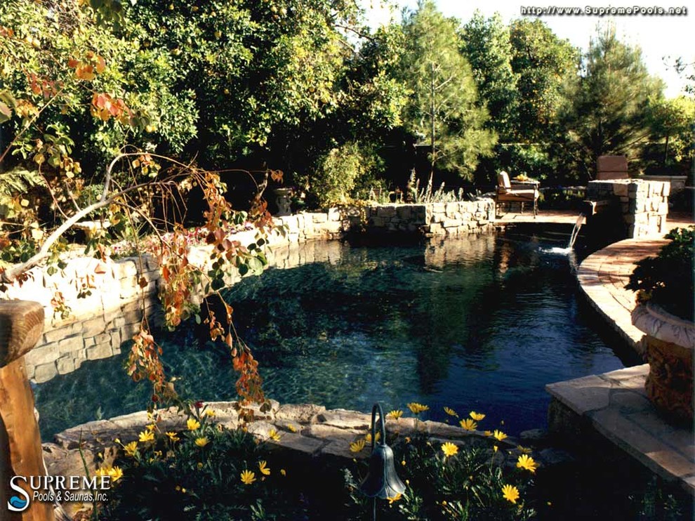 Esempio di una grande piscina naturale mediterranea personalizzata dietro casa con fontane e pavimentazioni in mattoni