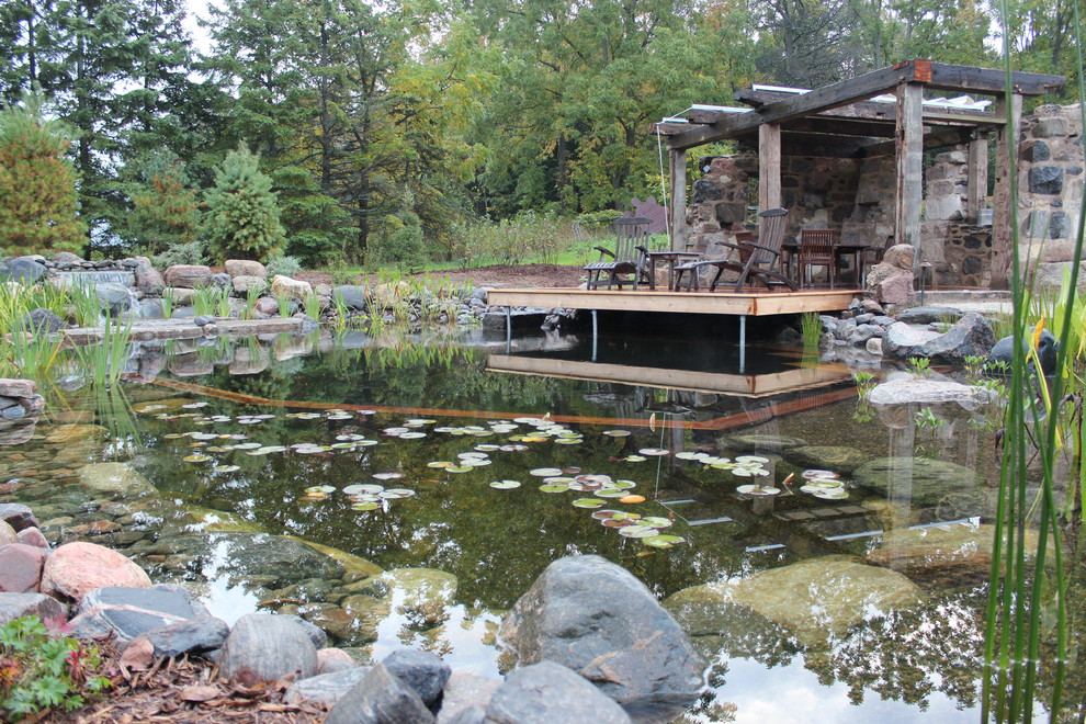 Aménagement d'une piscine naturelle et arrière montagne de taille moyenne et sur mesure avec un point d'eau et une terrasse en bois.