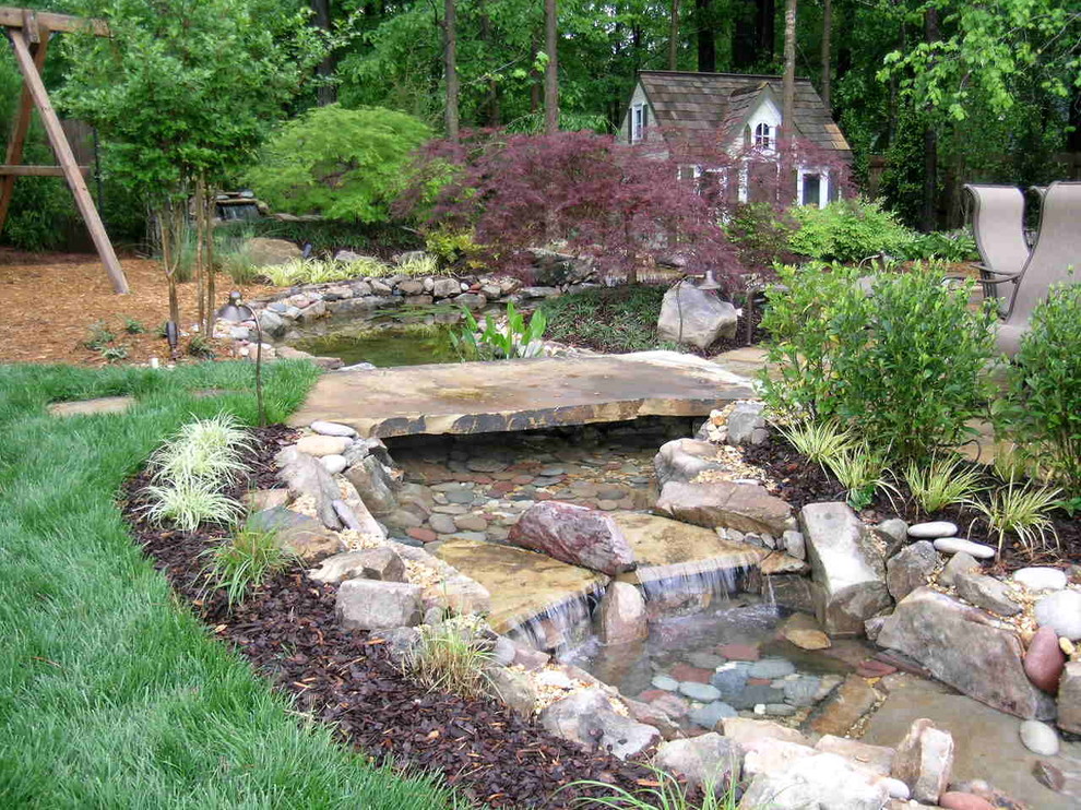 Immagine di un grande giardino tradizionale dietro casa con fontane e pavimentazioni in pietra naturale