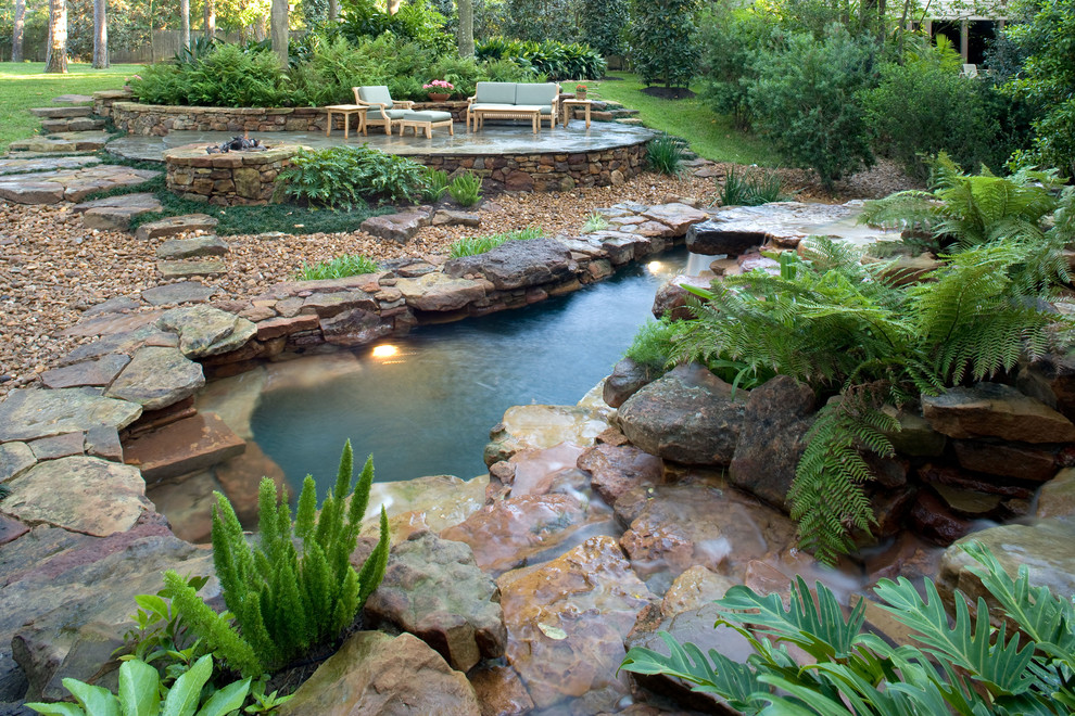 Diseño de piscina natural exótica de tamaño medio a medida en patio trasero con adoquines de piedra natural