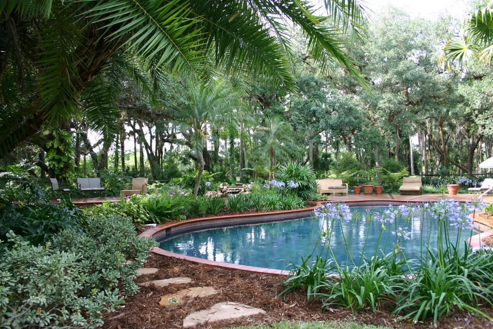 Ispirazione per una piscina monocorsia tropicale personalizzata dietro casa con fontane e piastrelle