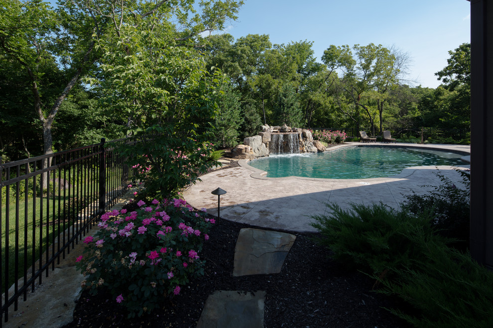 Foto de piscina natural rústica de tamaño medio a medida en patio trasero con suelo de hormigón estampado