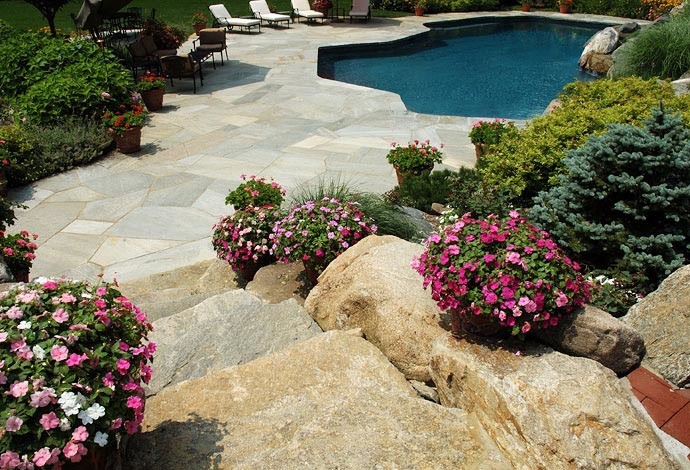 Ejemplo de piscina con fuente de tamaño medio a medida en patio trasero con adoquines de piedra natural