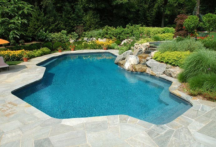 Modelo de piscina con fuente de tamaño medio a medida en patio trasero con adoquines de piedra natural