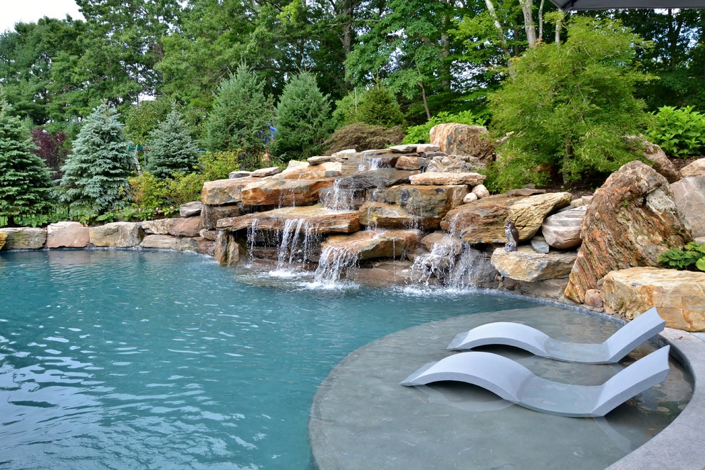 Large rustic back kidney-shaped natural swimming pool in New York with natural stone paving.