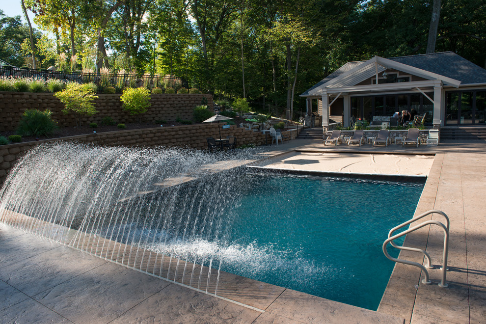 Photo of a large modern back rectangular swimming pool in Cedar Rapids with a water feature and stamped concrete.