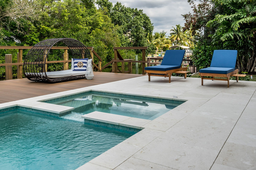 This is an example of a nautical back rectangular hot tub in Miami with natural stone paving.