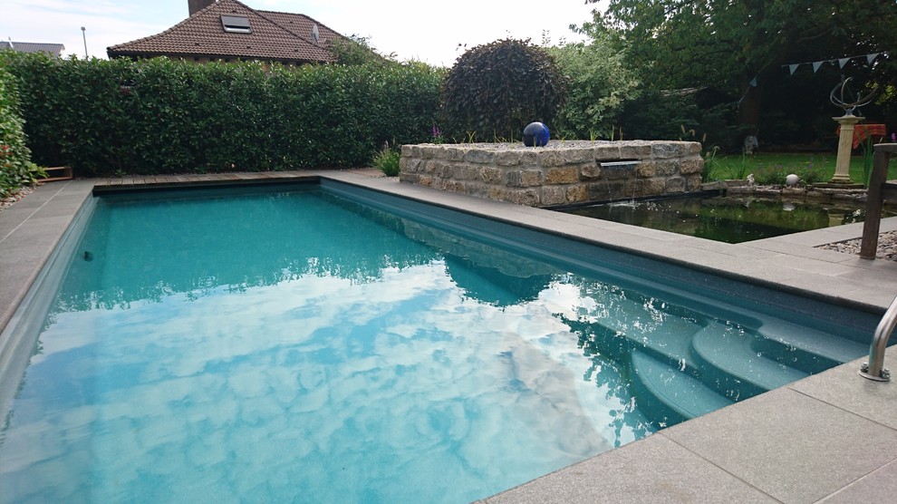 Imagen de piscina contemporánea grande rectangular en patio lateral con adoquines de piedra natural