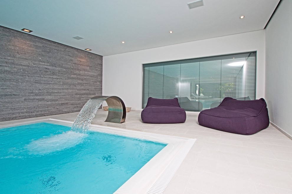 Photo of a medium sized contemporary indoor rectangular above ground swimming pool in Other with a water feature and tiled flooring.