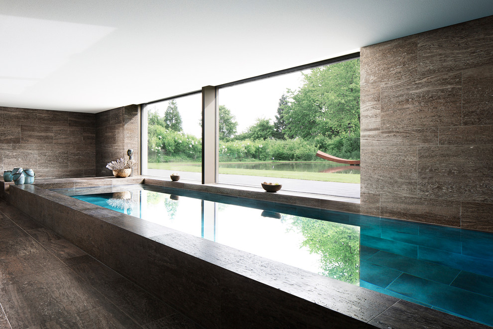 На фото: большой прямоугольный бассейн в доме в современном стиле с покрытием из каменной брусчатки