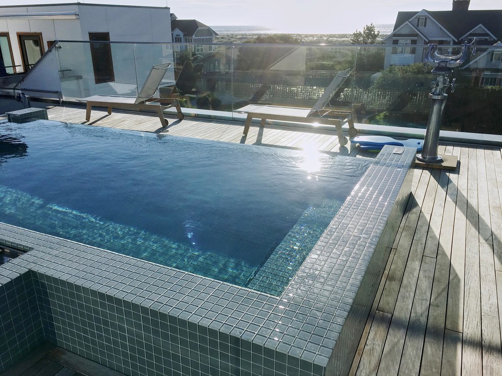 Exemple d'une piscine sur toit à débordement tendance rectangle avec une terrasse en bois.