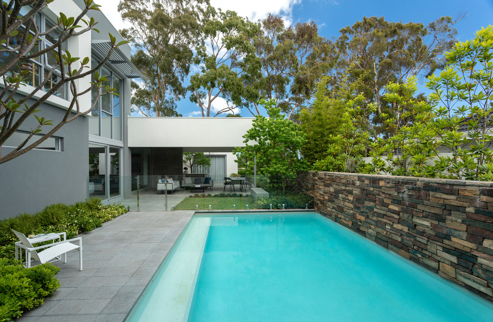 Foto di una piscina contemporanea rettangolare di medie dimensioni e dietro casa con pavimentazioni in pietra naturale