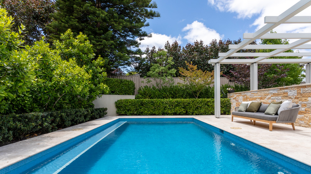 Imagen de piscina natural mediterránea de tamaño medio rectangular en patio trasero con adoquines de piedra natural