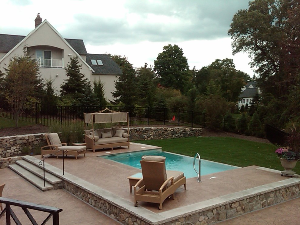 Modelo de piscina infinita clásica renovada pequeña rectangular en patio trasero con adoquines de piedra natural
