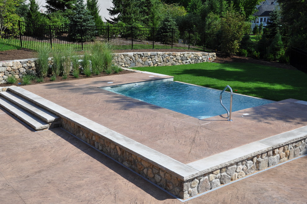 Ejemplo de piscina infinita clásica renovada pequeña rectangular en patio trasero con adoquines de piedra natural