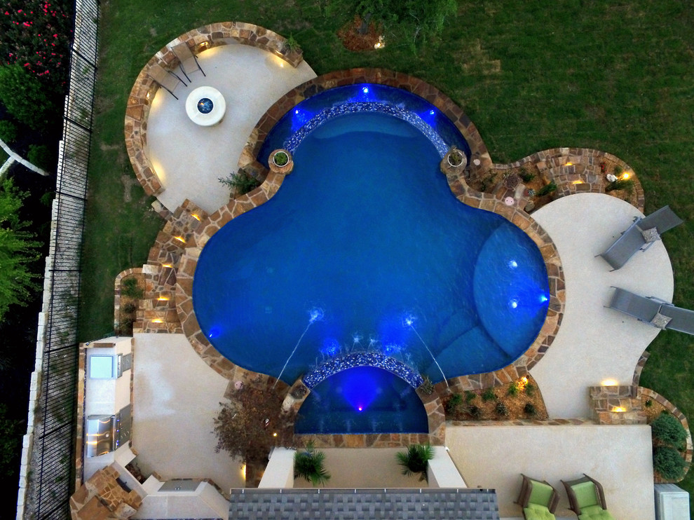 Imagen de piscinas y jacuzzis infinitos exóticos grandes a medida en patio trasero con losas de hormigón