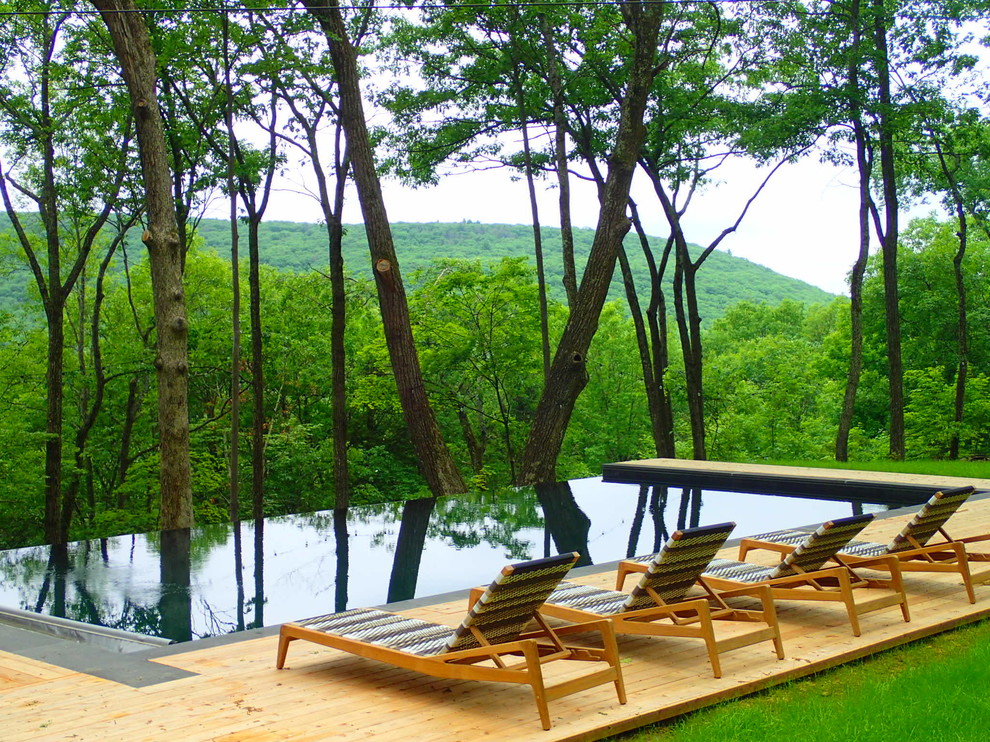 Idée de décoration pour une piscine à débordement et arrière design rectangle avec une terrasse en bois.
