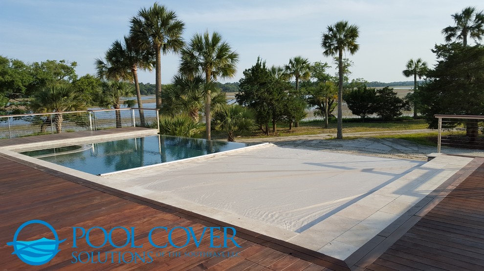 Aménagement d'une grande piscine à débordement et arrière contemporaine rectangle avec une terrasse en bois.